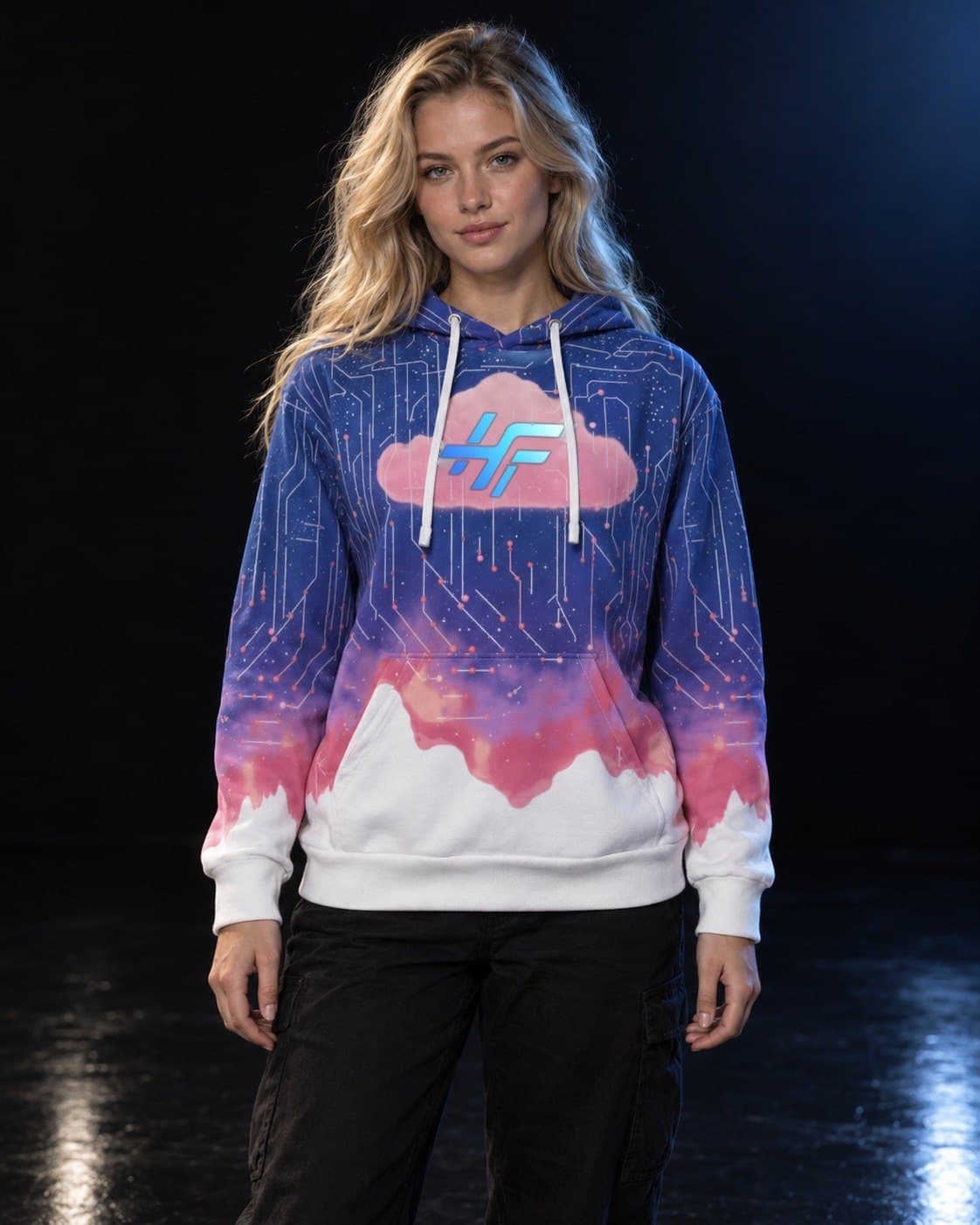A woman with long blonde hair in a dark studio, wearing the Cloud Hoodie